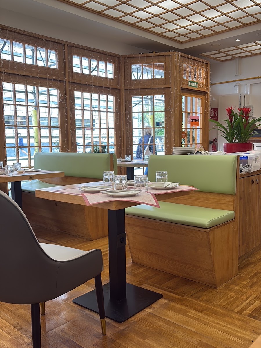 Comedor con mesas de madera, asientos verdes y techo enrejado